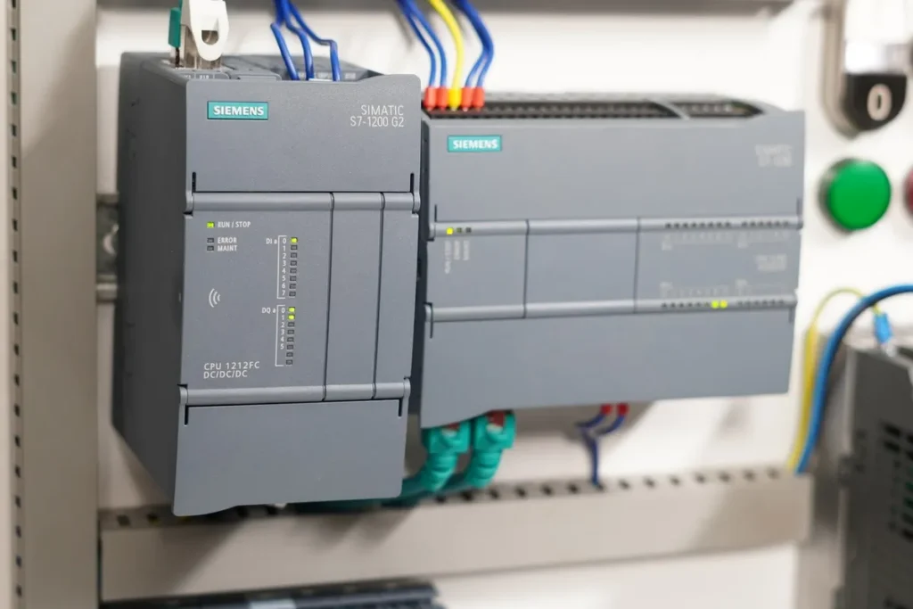 Sterownik Siemens S7-1200 z modułami rozszerzeń i przyciskami sterowniczymi na stanowisku