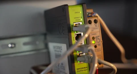 Router zdalnego dostępu Secomea SiteManager na szynie DIN z podłączonymi przewodami Ethernet